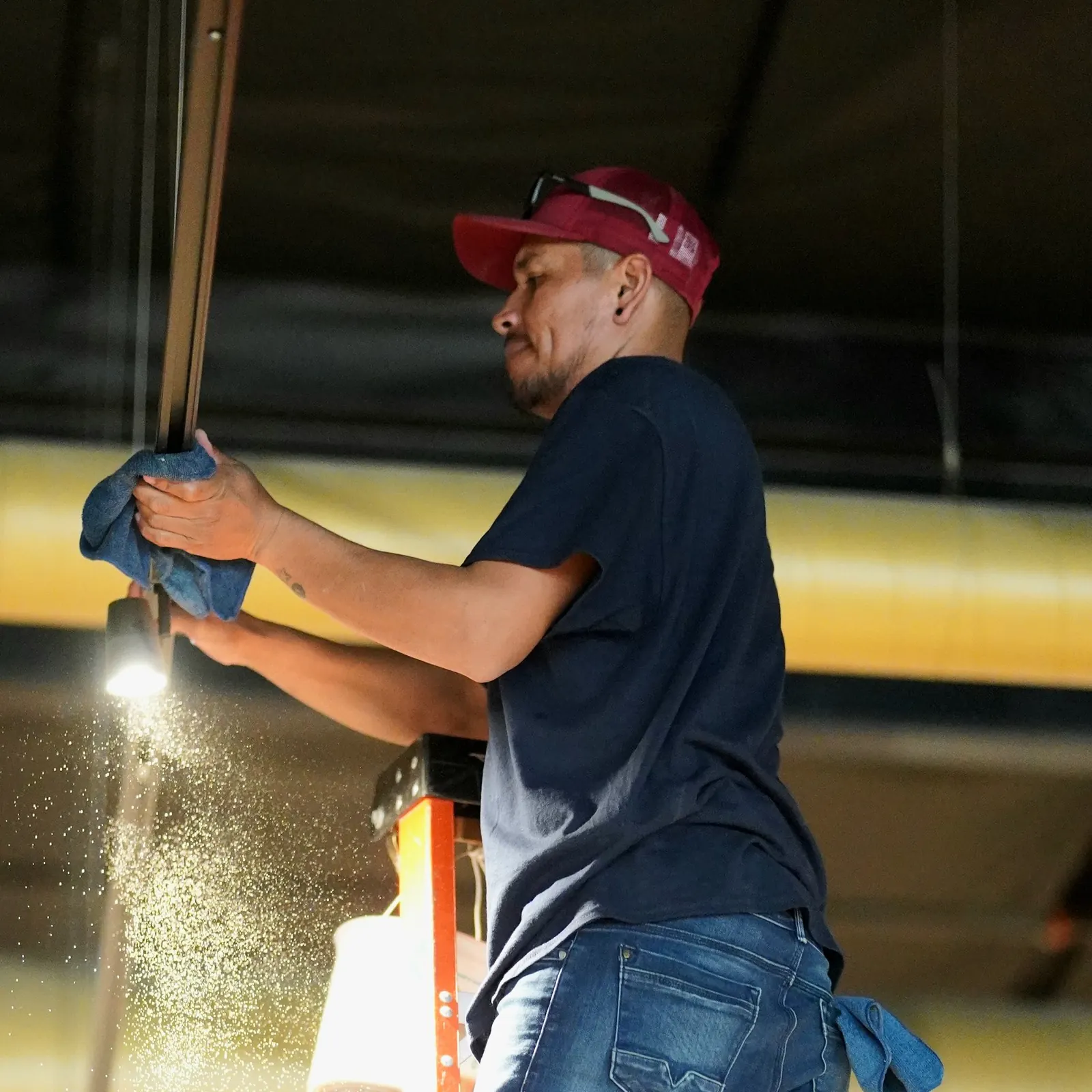 Reno Clean crew member dusting overhead from a ladder