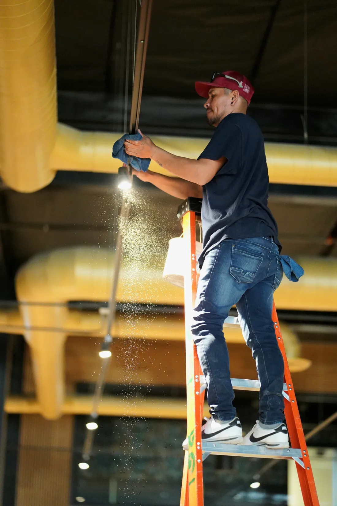 Rough clean phase: crew member taking down dust from a ladder